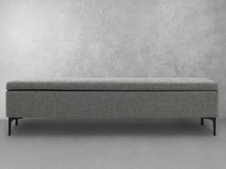 A grey bench featuring black legs and a gray upholstered seat, designed for comfort and style in any setting