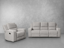 A grey reclining couch and chair positioned in front of a plain wall, creating a cozy seating area