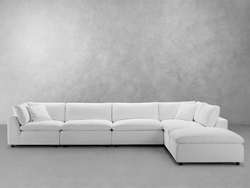 A white sectional couch adorned with a matching white cushion, creating a clean and modern living space aesthetic